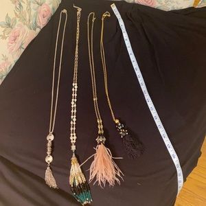 4 necklaces with tassels and embellishments.